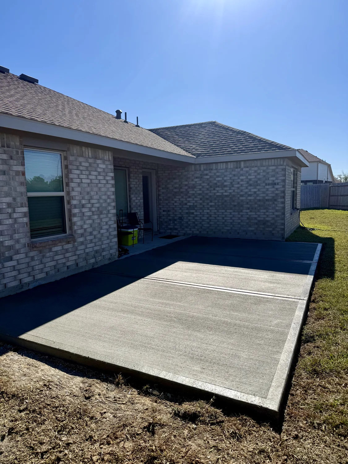 Clean finished broom-finish concrete patio in a backyard
